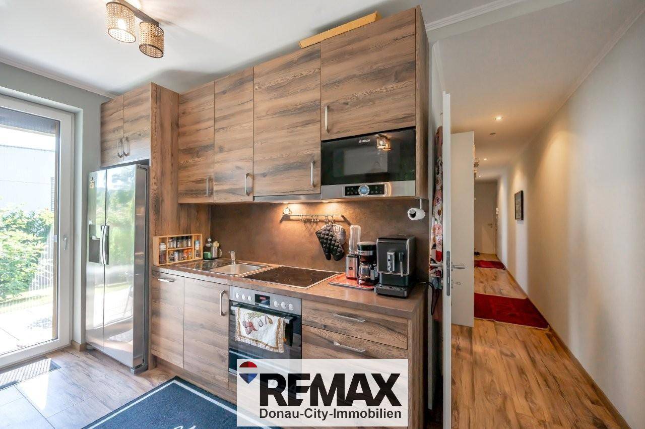 Moderne Holzküche mit integrierten Geräten und einem angrenzenden Flur mit Holzboden.