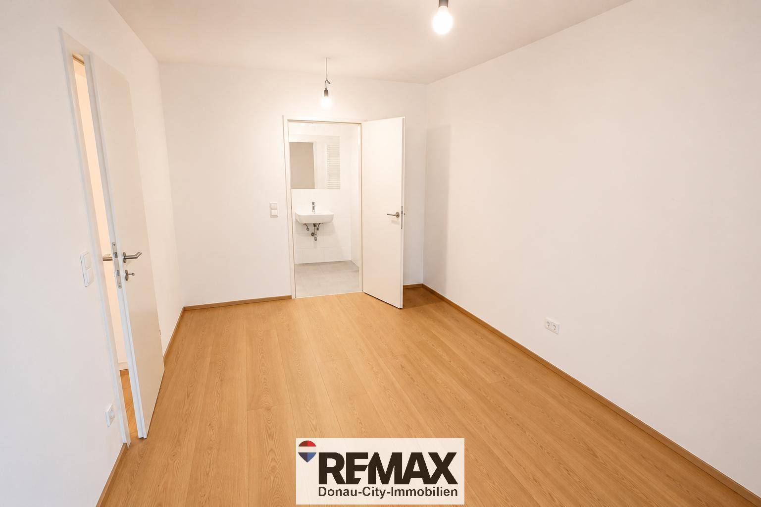 Unmöbliertes Schlafzimmer mit Holzboden und Zugang zu einem angrenzenden Badezimmer oder Gäste-WC.
