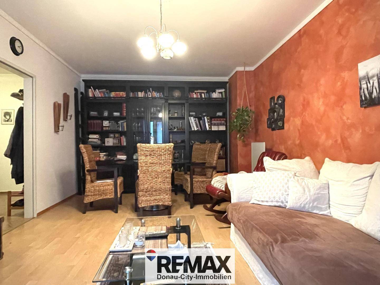 Wohnzimmer mit Bücherregal, Esstisch und rustikalen Korbstühlen.