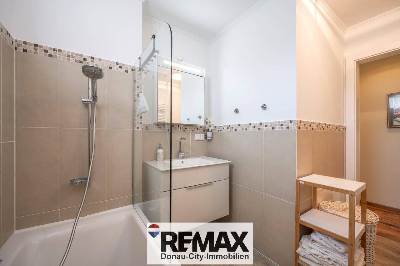 Modernes Badezimmer mit Badewanne, Duschfunktion und eleganten Fliesen.