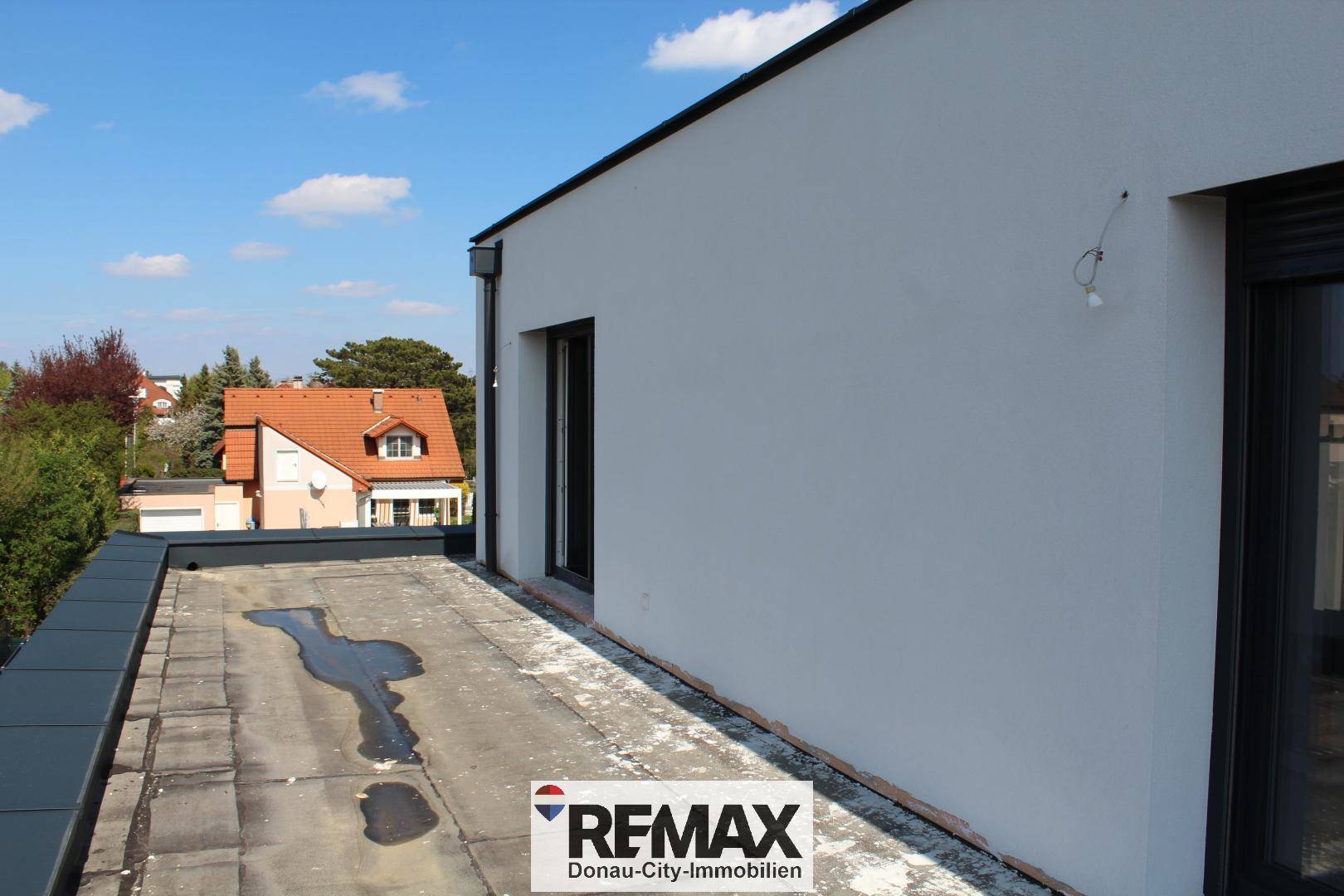 Unfertige Dachterrasse mit weitem Blick über die umliegenden Dächer und die Nachbarschaft.