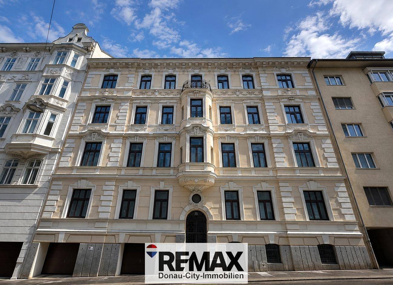 Historische Fassade eines Altbaus mit eleganten Verzierungen und vielen Fenstern.