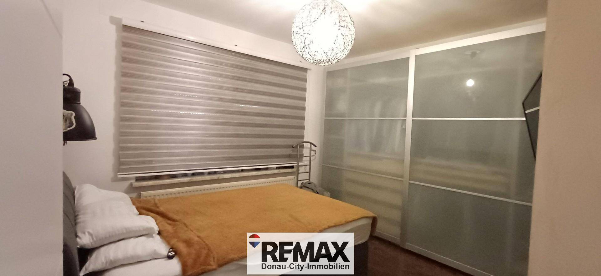 Gemütliches Schlafzimmer mit Bett, großem Fenster und praktischem Einbauschrank.