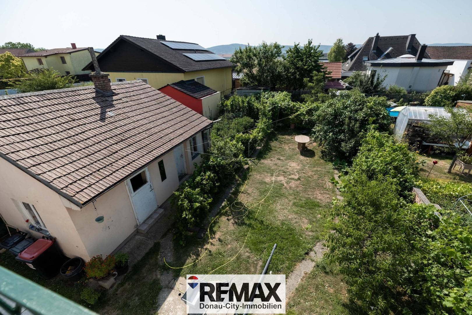 Großer Gartenbereich mit Rasenfläche, Bäumen und einem kleinen Tisch im Freien.