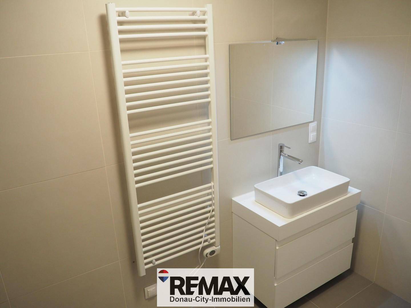 Badezimmer mit beheiztem Handtuchhalter, Spiegel und modernem Aufsatzwaschbecken.