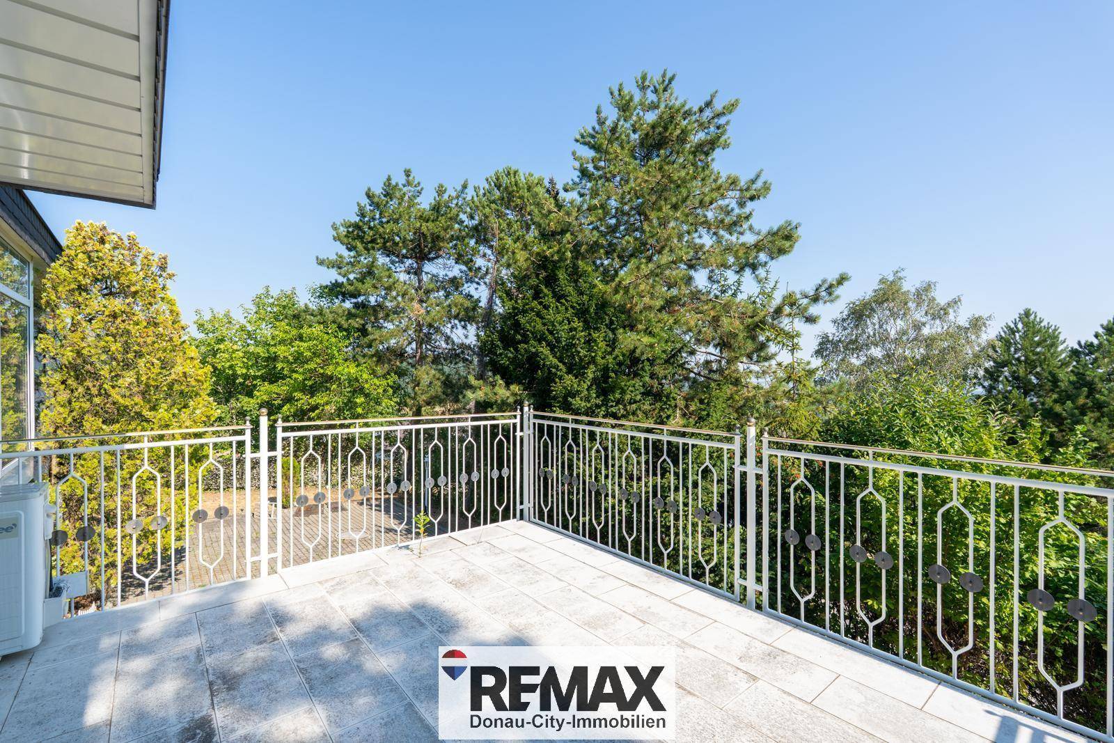 Geräumiger Balkon mit weißem Metallgeländer und weitem Blick ins Grüne.