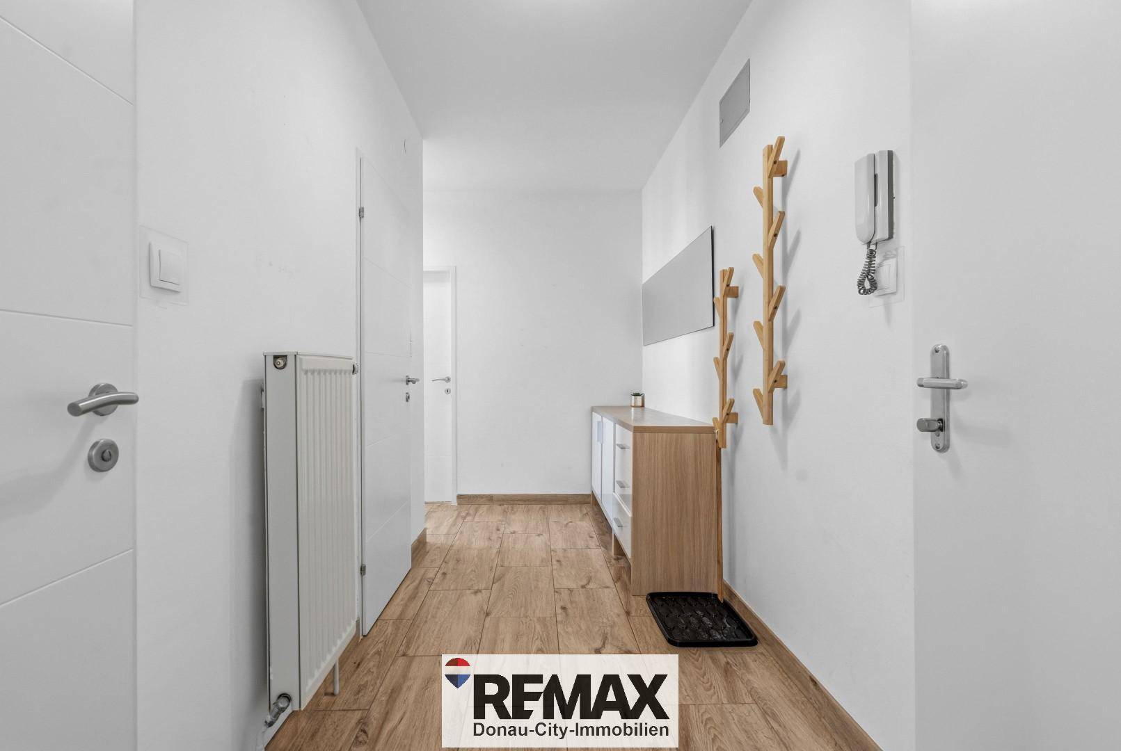 Heller Flur mit Laminatboden, Heizkörper und Garderobe, bietet einen freundlichen Empfangsbereich.
