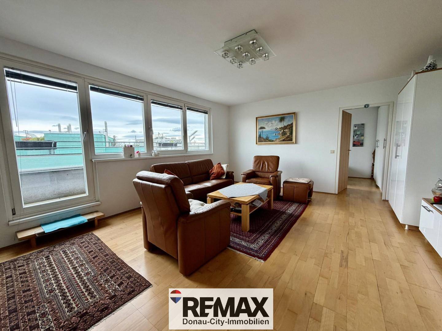 Helles Wohnzimmer mit Ledersofas, Parkettboden und Zugang zu einem Außenbereich.