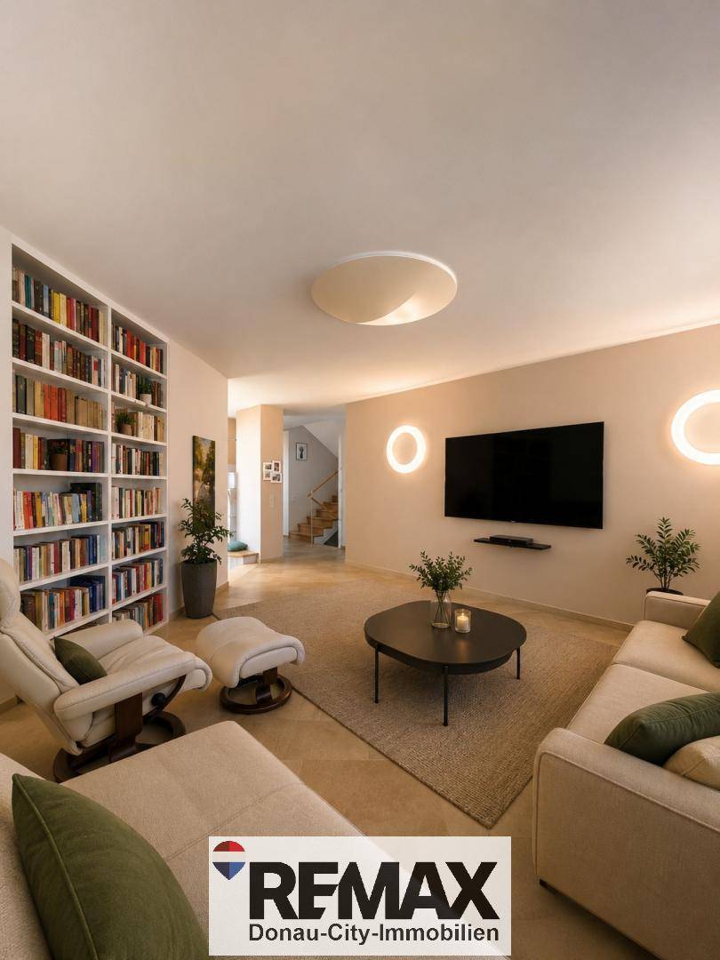 Geräumiges Wohnzimmer mit großem Bücherregal, bequemer Couch und modernem Fernseher an der Wand.