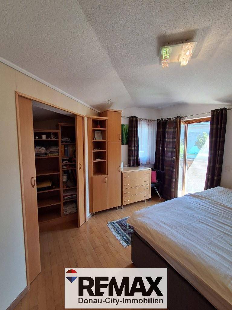 Helles Schlafzimmer mit Holzboden, Kleiderschrank und direktem Zugang zu einem Außenbereich.