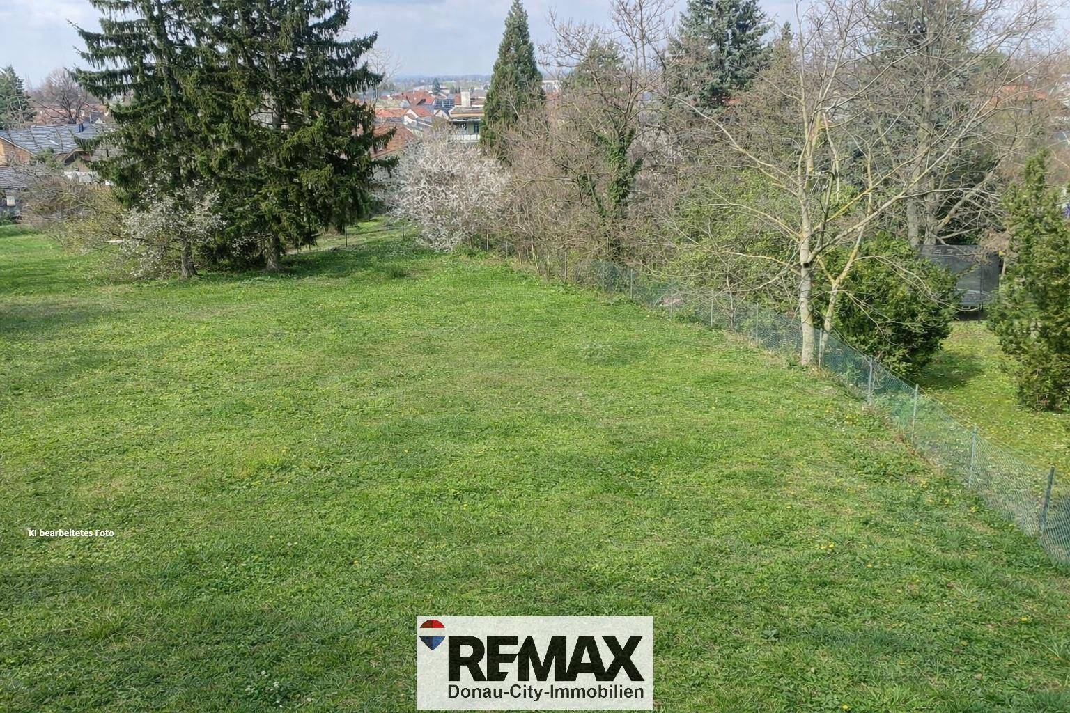 Grüne Wiese mit Bäumen im Hintergrund und einem Zaun, ideal für einen Garten.