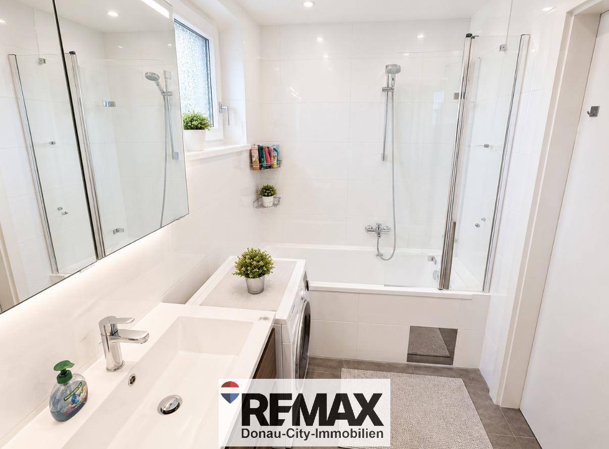 Helles Badezimmer mit Badewanne, Dusche, Waschbecken und Fenster.