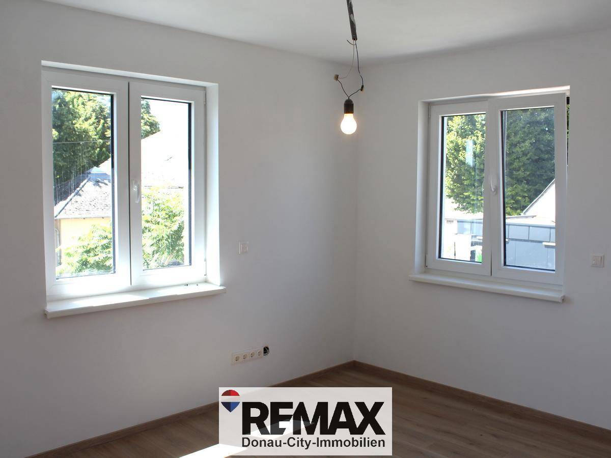 Helles Zimmer mit zwei Fenstern und Laminatboden, ideal als Schlaf- oder Arbeitszimmer nutzbar.