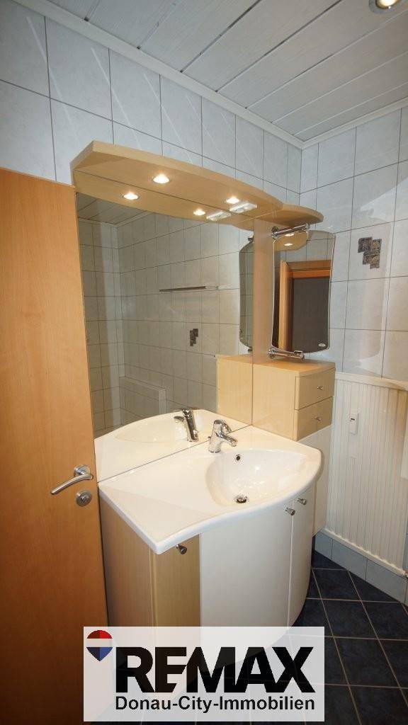 Badezimmer mit modernem Waschbecken und großem Spiegel, hell gefliest und gut beleuchtet.
