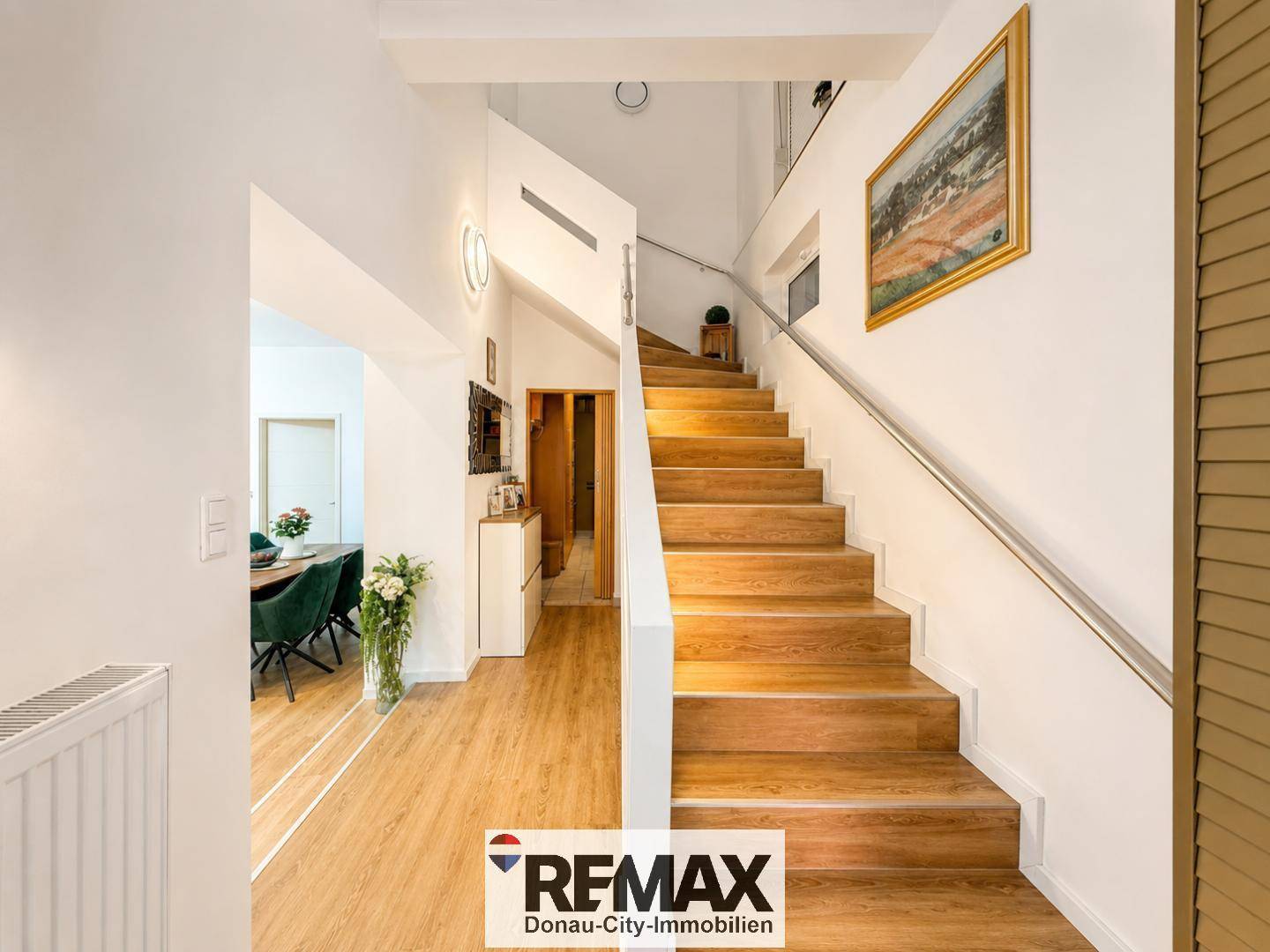 Geräumiger Flur mit Holztreppe und modernem Design, der die Ebenen verbindet.