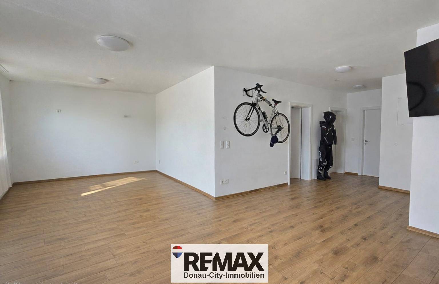 Geräumiger, heller Raum mit Holzboden und einer Wandhalterung für ein Fahrrad.
