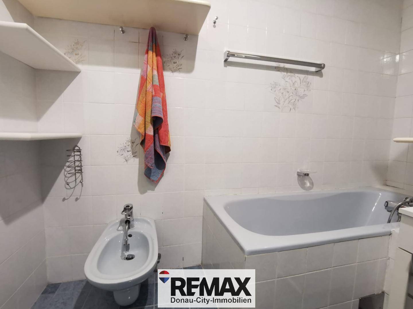Badezimmer mit Badewanne, Bidet und weißen Fliesen an den Wänden.