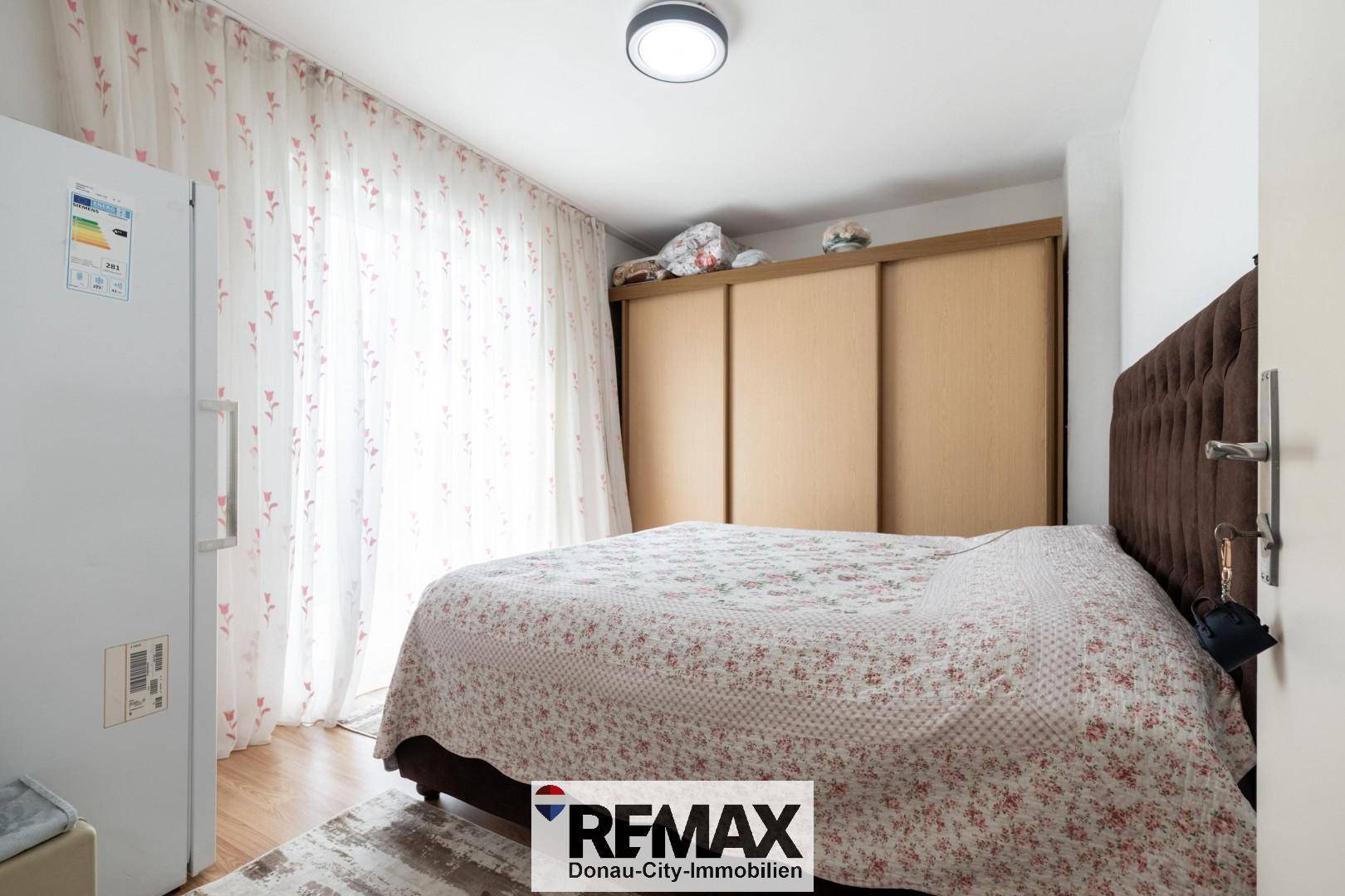 Schlafzimmer mit Doppelbett, Schiebetürenschrank und hellem Fenster.