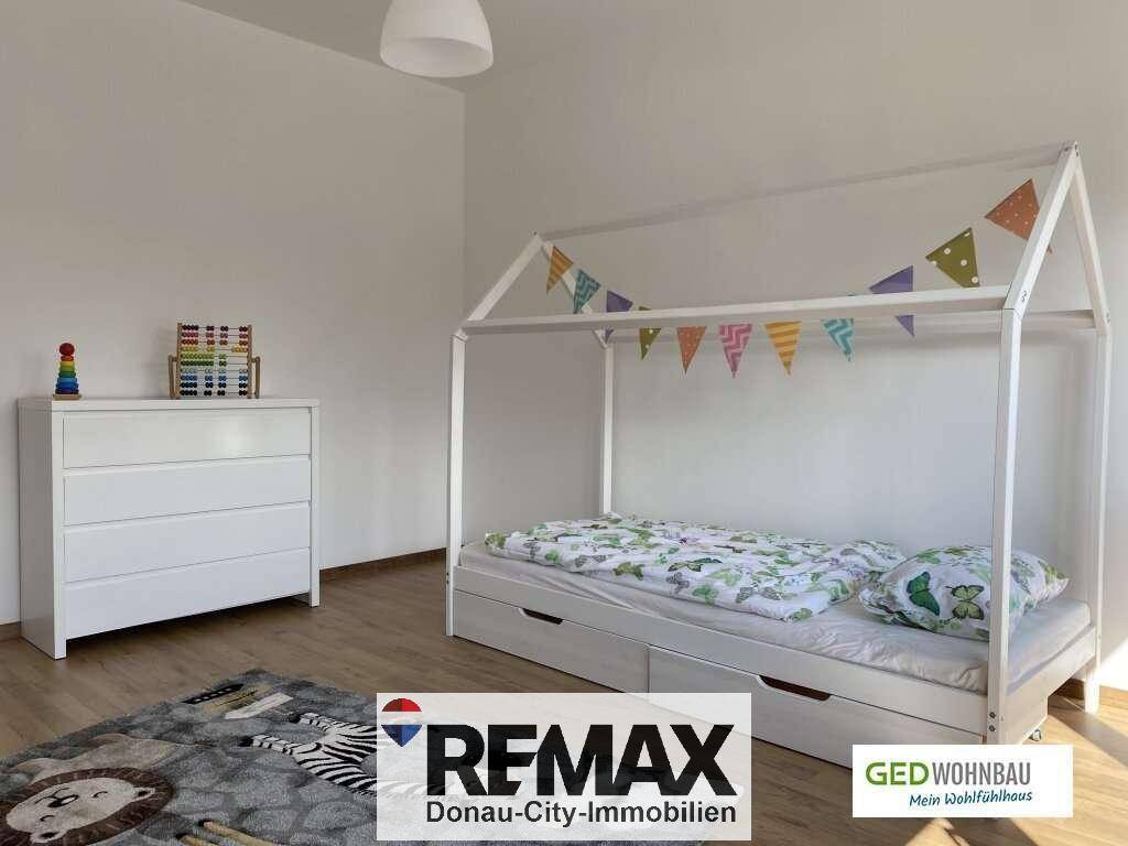 Helles Kinderzimmer mit modernem Hausbett und weißer Kommode, freundlich dekoriert.