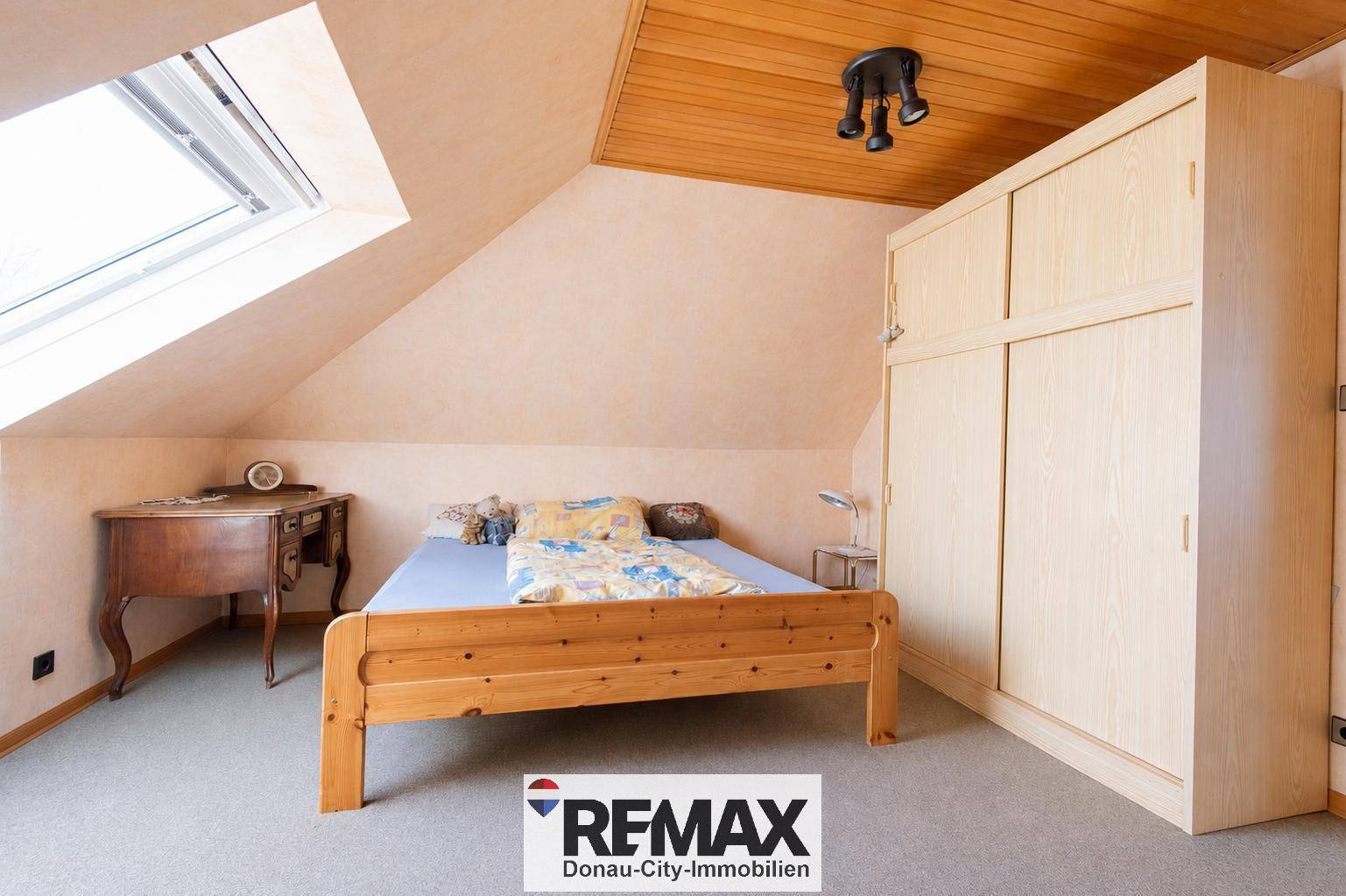 Schlafzimmer im Dachgeschoss mit Holzbett, Kleiderschrank und Dachfenster, bietet eine ruhige Atmosphäre.