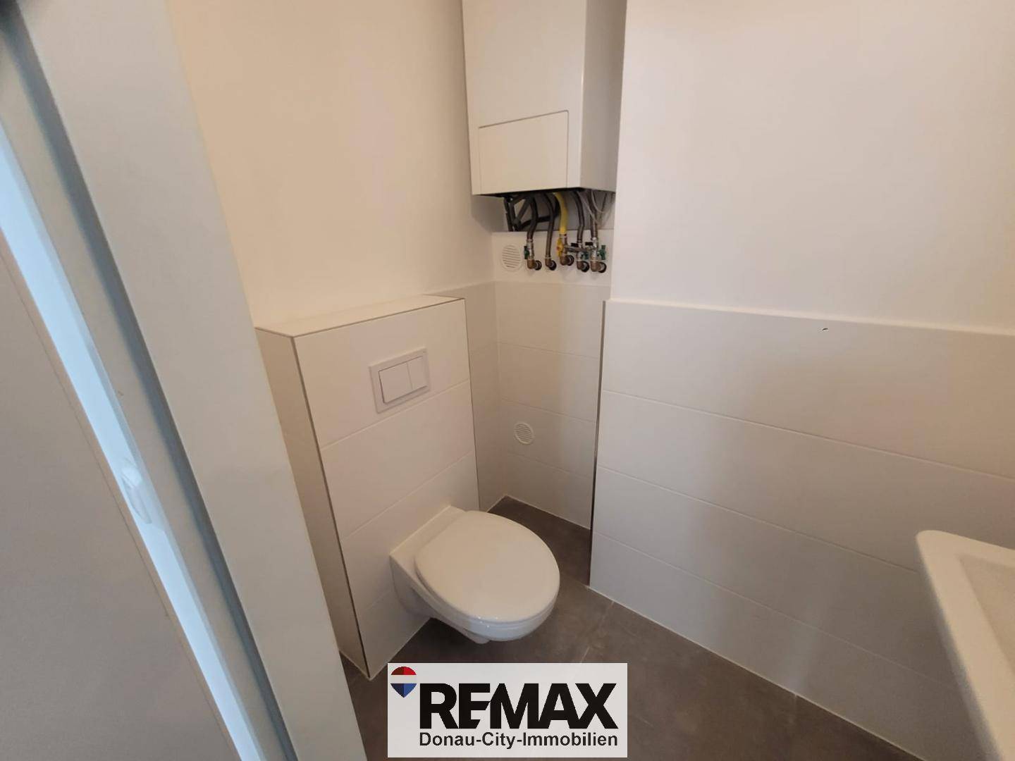 Kompaktes Gäste-WC mit wandhängender Toilette und einem Heizkessel an der Wand.