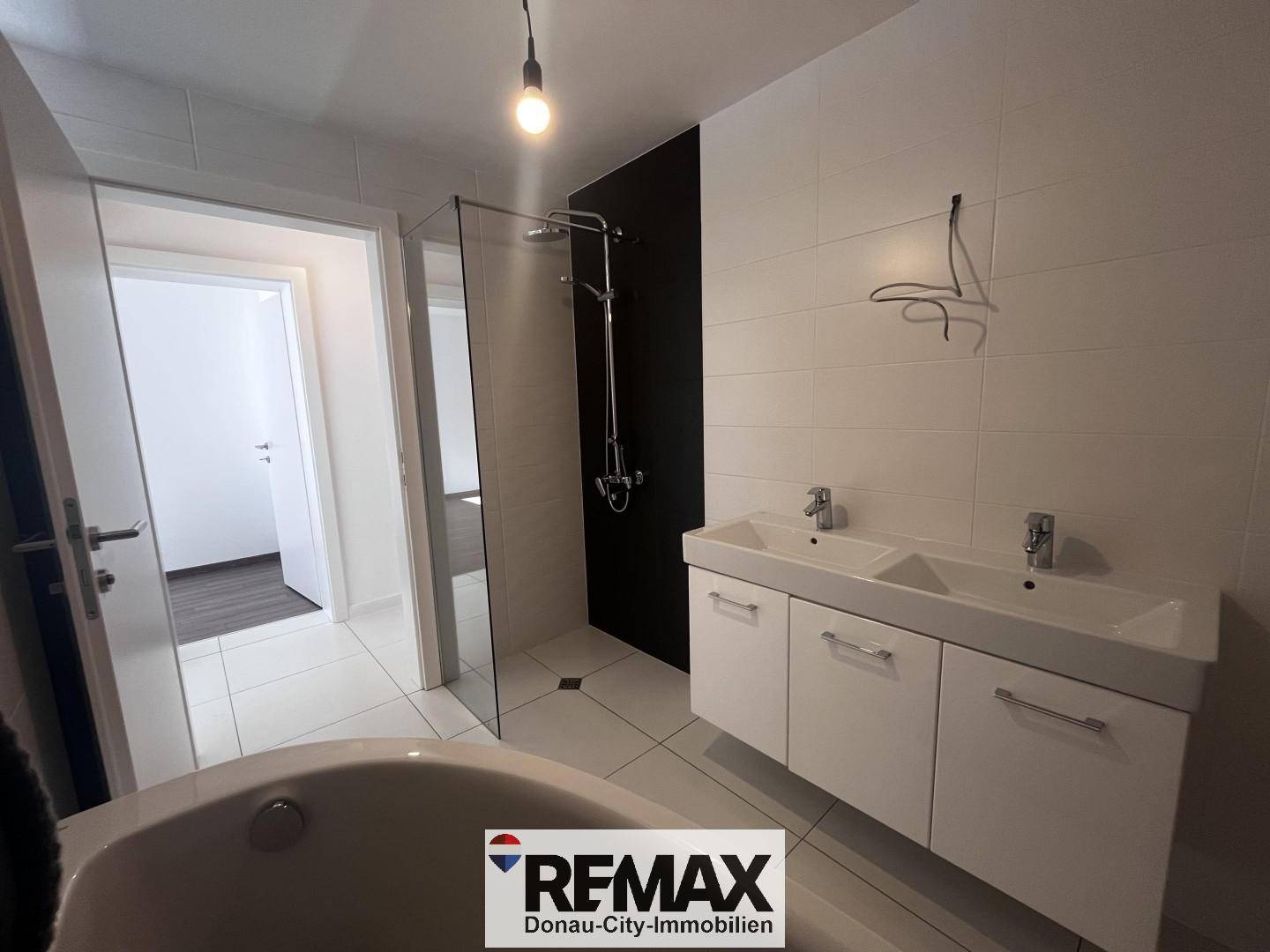 Modernes Badezimmer mit begehbarer Dusche, Doppelwaschbecken und einer eleganten Eckbadewanne.