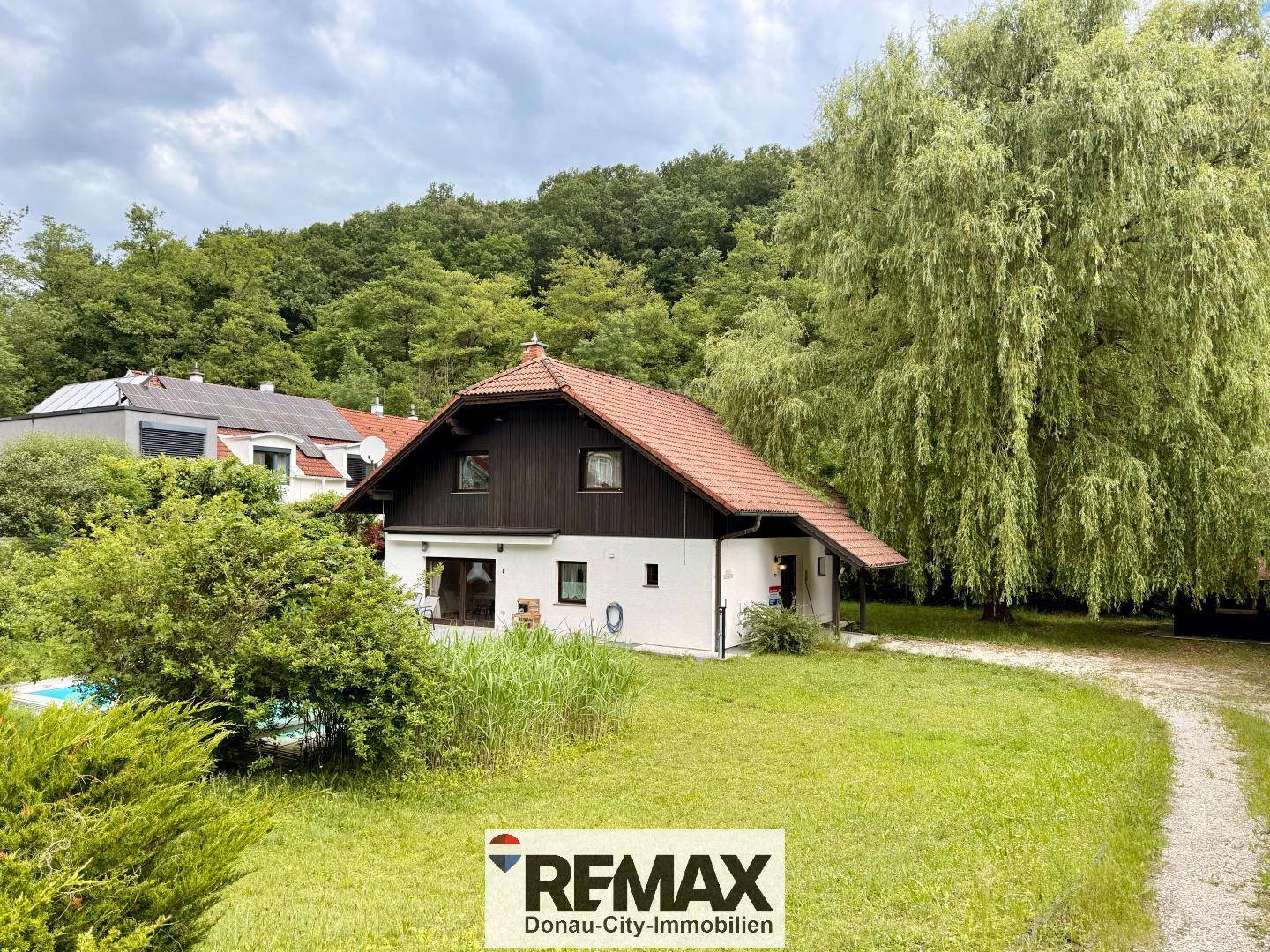 Gesamtansicht des Hauses mit großem Garten, Zufahrt und umgebender grüner Landschaft.