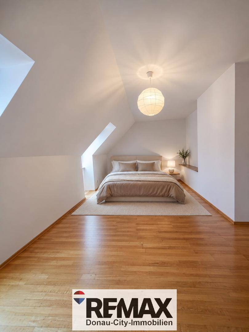 Gemütliches Schlafzimmer mit Holzboden, Dachschräge und indirekter Beleuchtung.