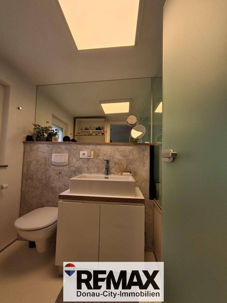 Modernes Badezimmer mit Waschtisch, WC und großer Spiegelfläche.