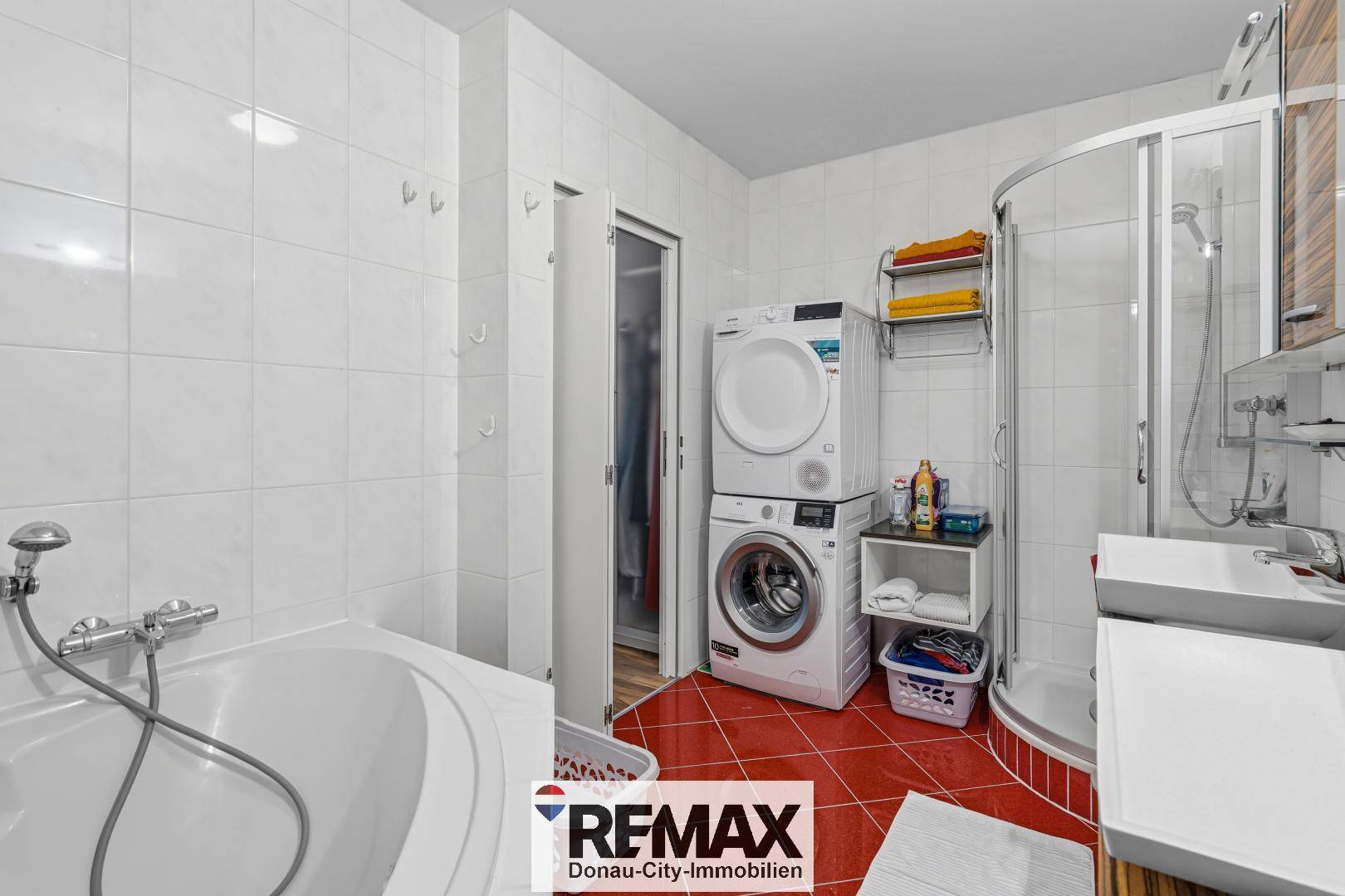 Funktionales Badezimmer mit Badewanne, Dusche und Waschmaschine/Trockner-Turm.