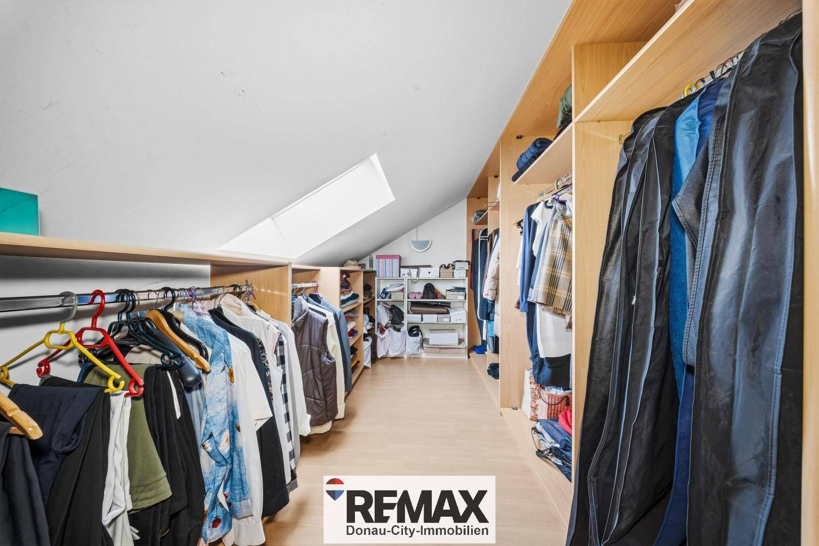Begehbarer Kleiderschrank im Dachgeschoss mit Regalen und Kleiderstangen, unter der Dachschräge.