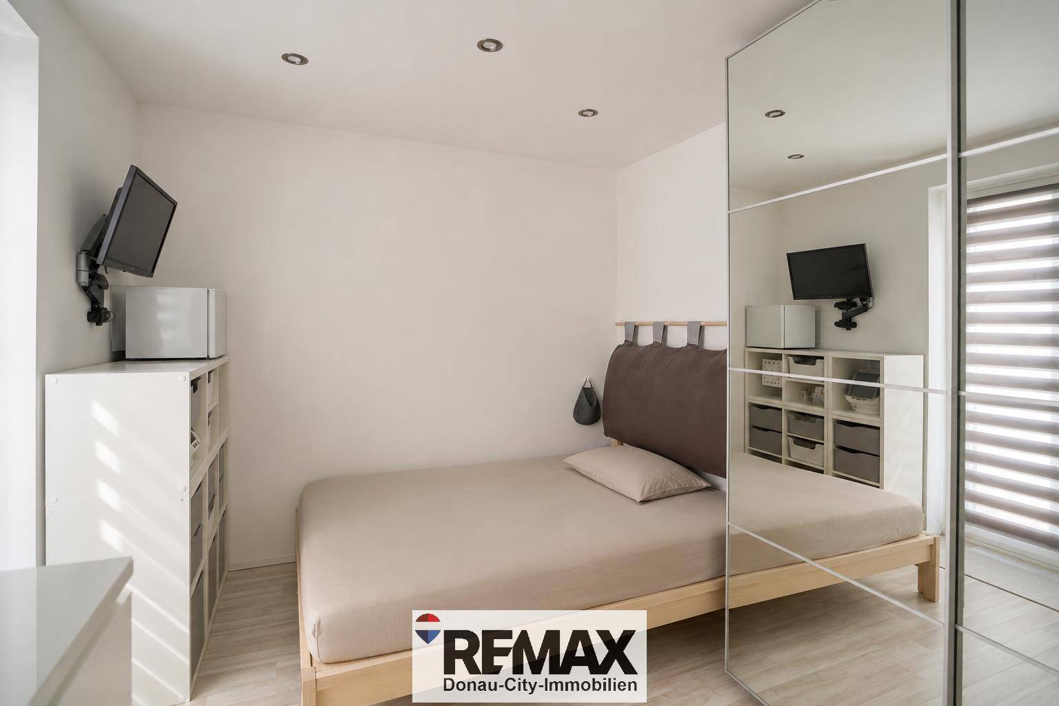 Schlafzimmer mit Doppelbett, Spiegelschrank und integrierter Beleuchtung.