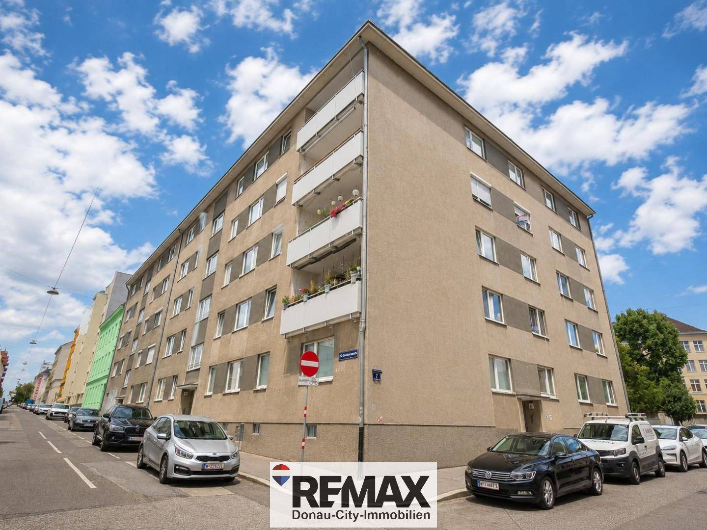 Mehrstöckiges Wohngebäude mit Balkonen und vielen Fenstern, gelegen an einer städtischen Straße.