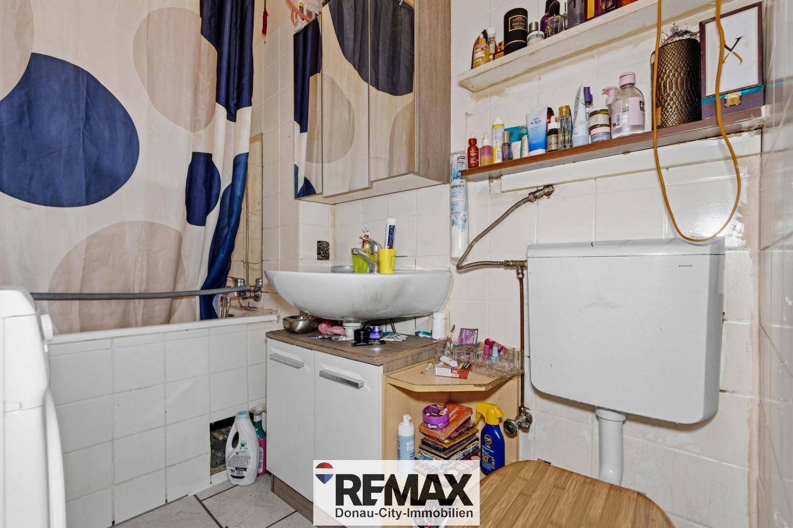 Badezimmer mit Badewanne, Waschbecken, Toilette und Waschmaschine, komplett gefliest.