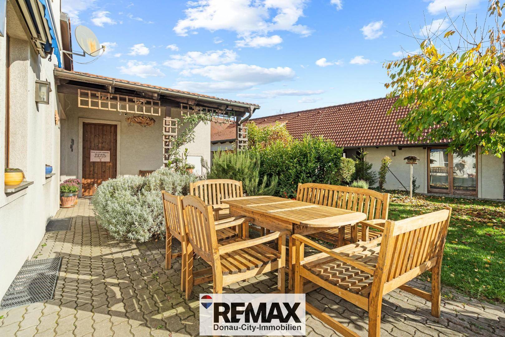 Gepflasterte Terrasse mit Holztisch und Stühlen, ideal für Mahlzeiten im Freien und Entspannung.