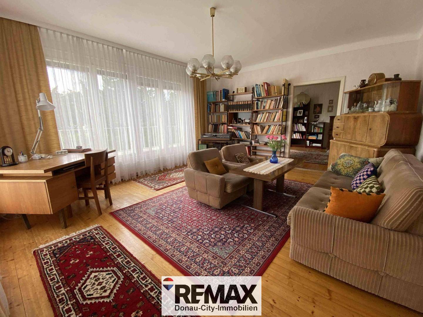 Gemütliches Wohnzimmer mit Schreibtisch, Sofa und Bücherregalen.