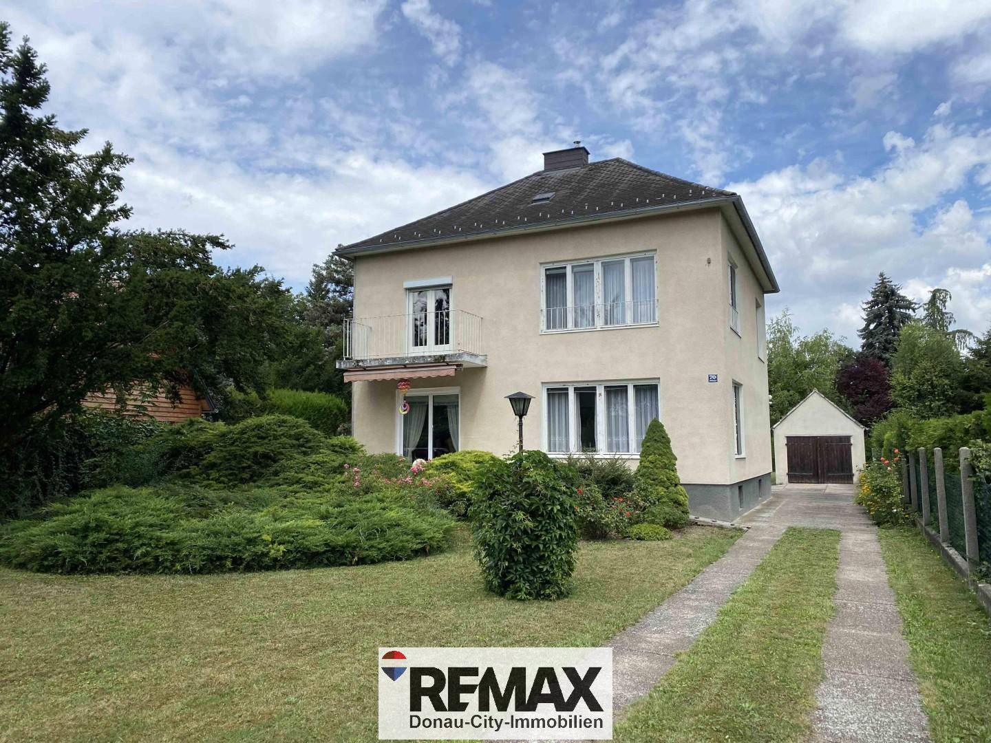 Einfamilienhaus mit kleinem Balkon und großem Gartenbereich.
