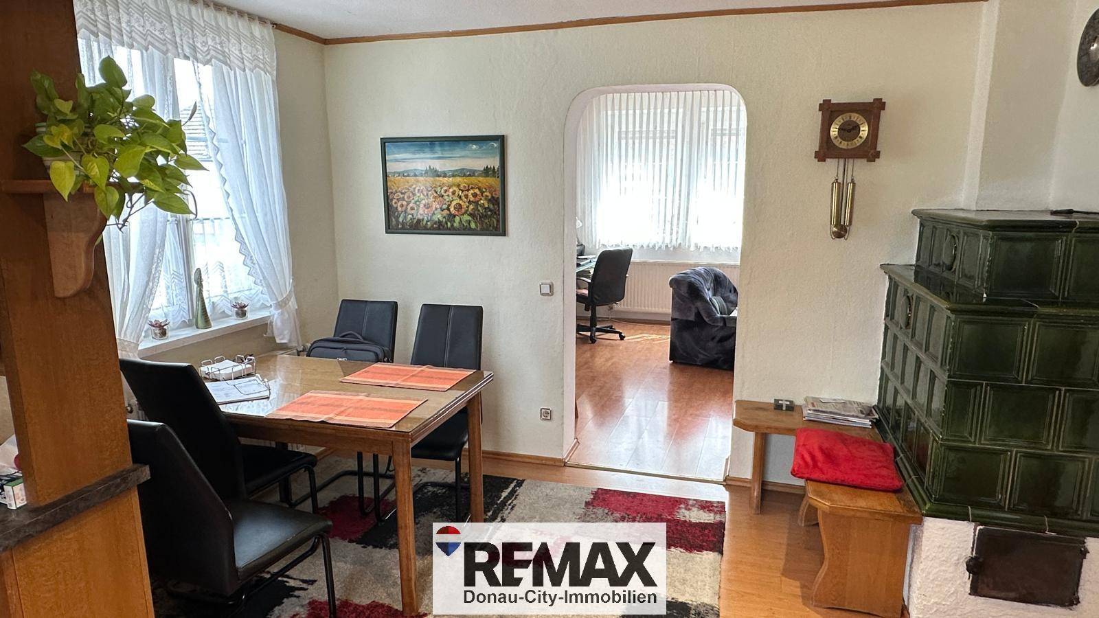 Gemütlicher Essbereich mit traditionellem Kachelofen und Zugang zu einem weiteren Zimmer.