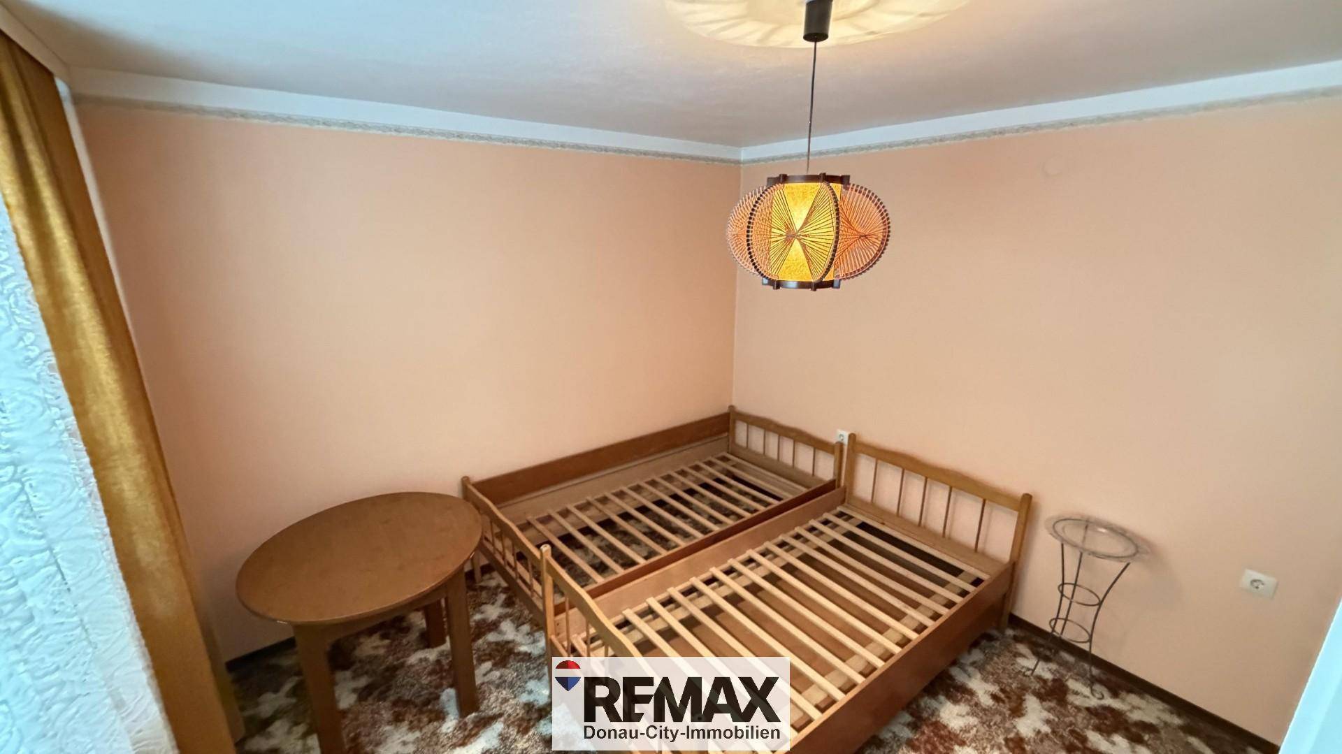 Schlafzimmer mit zwei Einzelbetten und einem kleinen Tisch, ausgestattet mit Teppichboden.