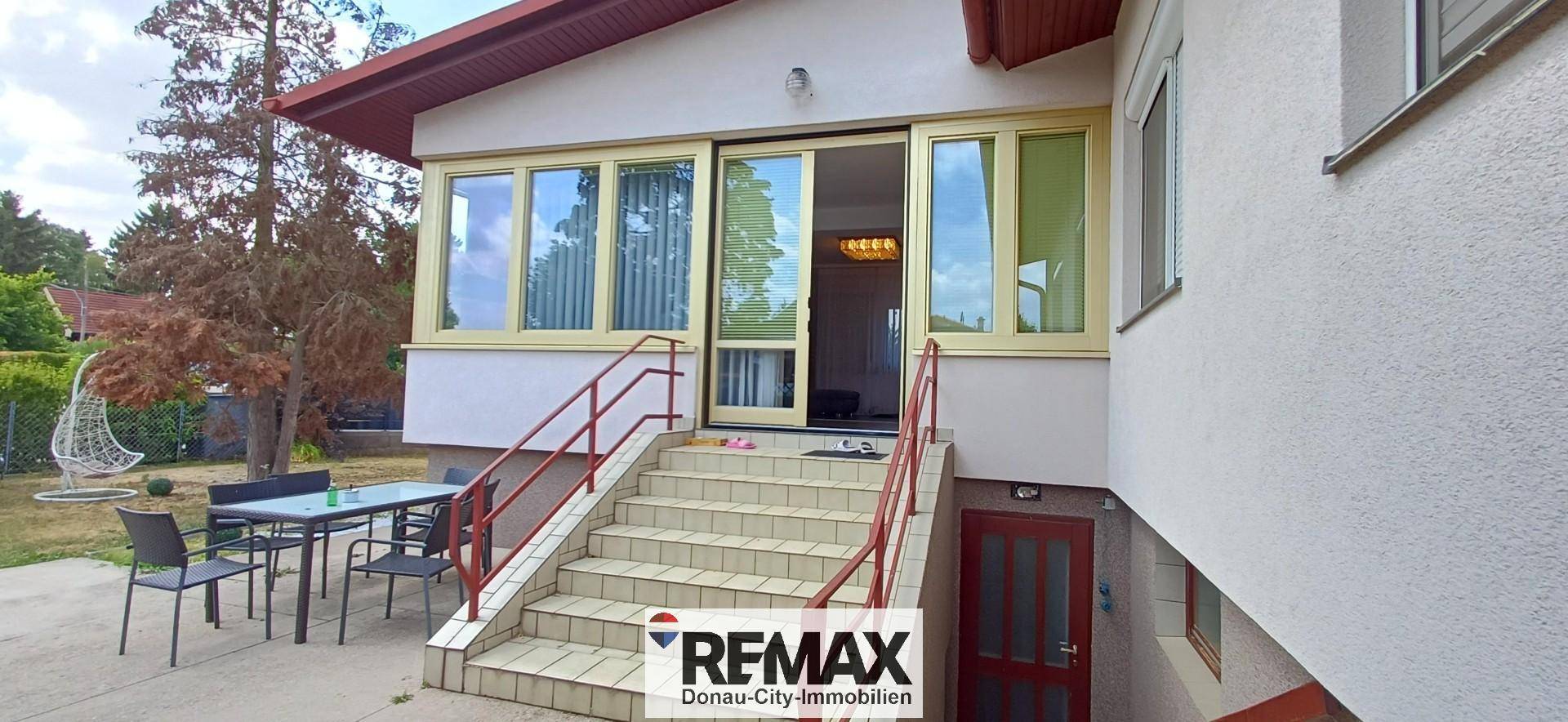 Eingangsbereich des Hauses mit Treppe, die zu einem verglasten Anbau führt.