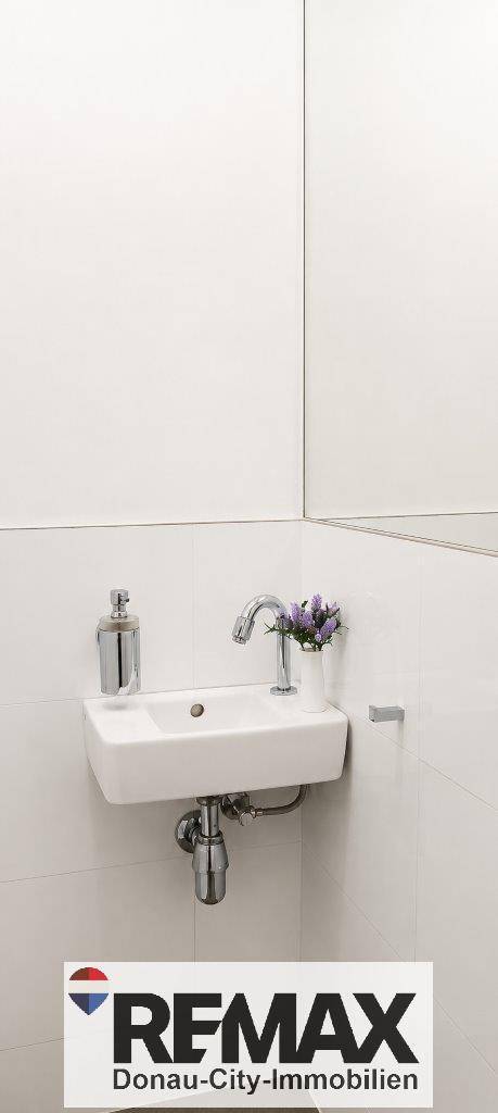 Kleines WC mit modernem Waschbecken und großem Spiegel.