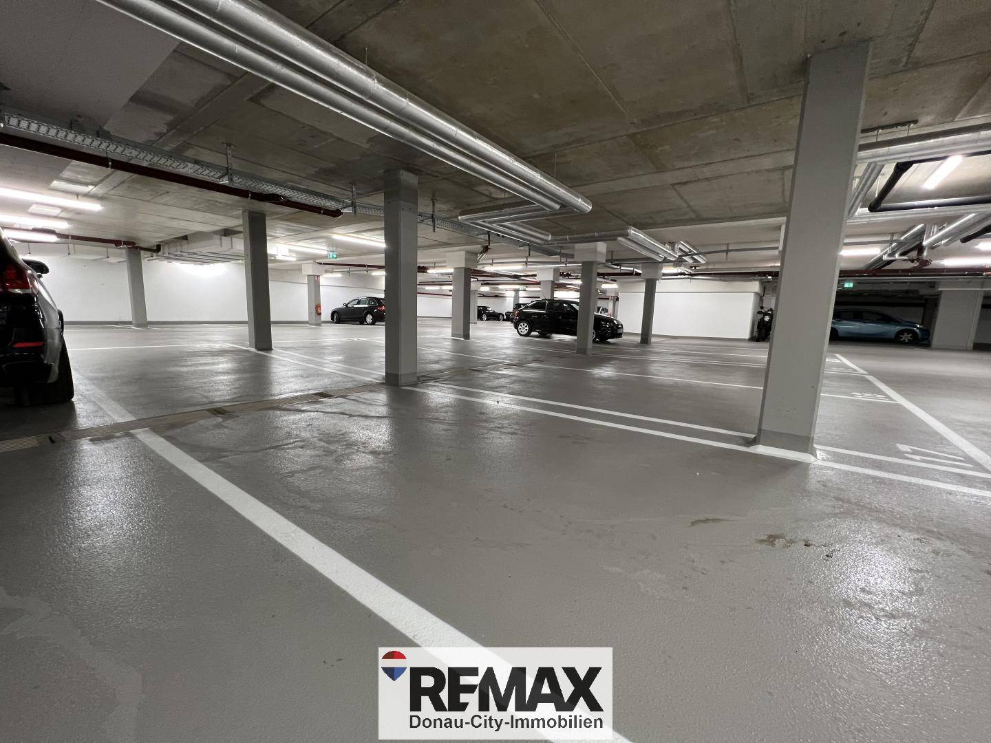 Weitläufige Tiefgarage mit zahlreichen Stellplätzen und tragenden Betonsäulen.