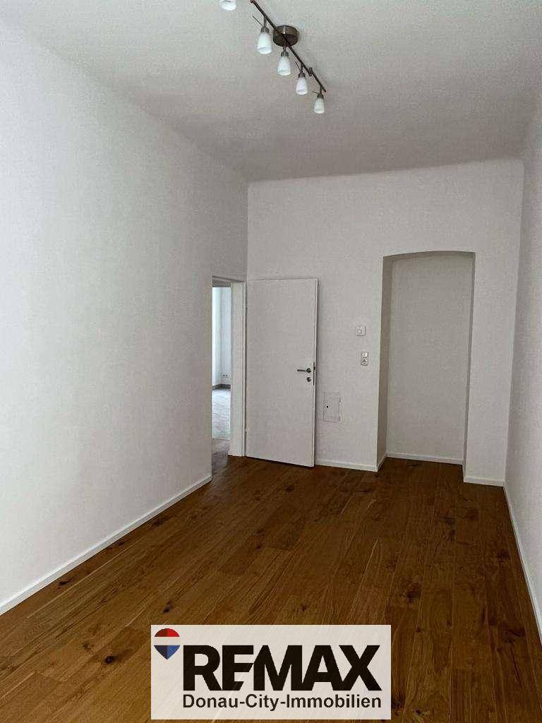 Heller Raum mit Holzboden und weiß gestrichenen Wänden, bereit zur individuellen Gestaltung.
