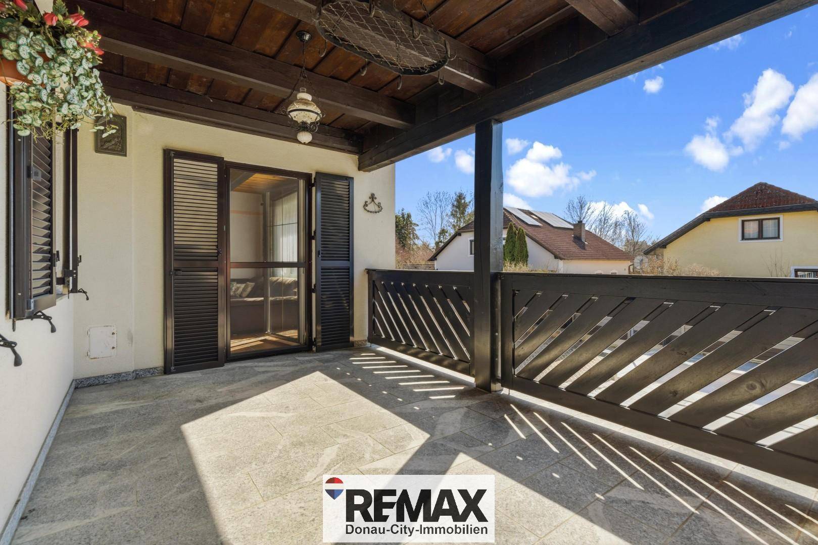 Sonnige überdachte Terrasse mit Fliesenboden und Holzbalken, ideal für entspannte Stunden im Freien.