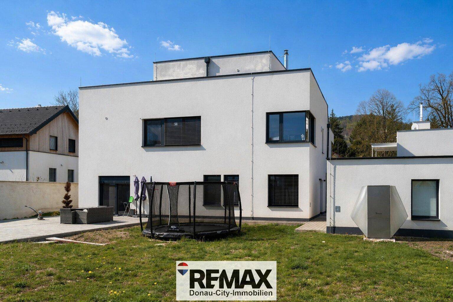 Rückseite des modernen Hauses mit Garten, Rasenfläche und Trampolin.