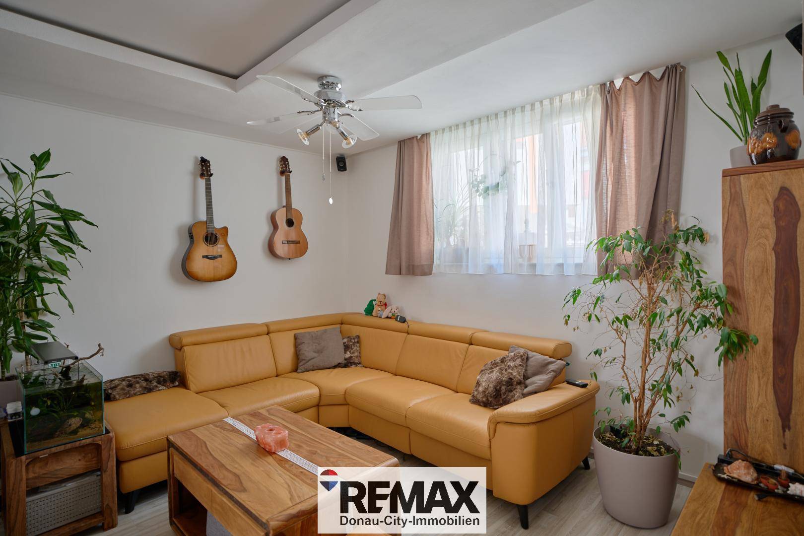 Gemütliches Wohnzimmer mit großer Eckcouch, Deckenventilator und viel Tageslicht.