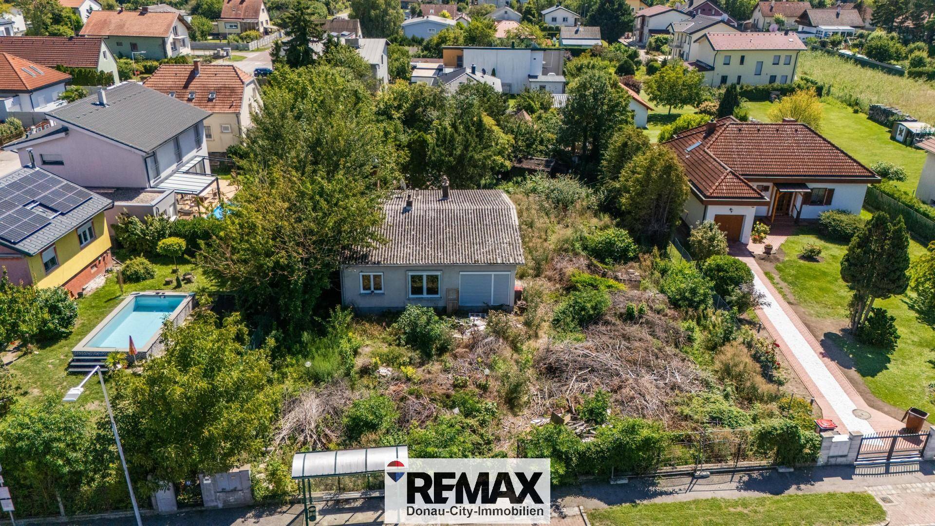 Blick von oben auf das Grundstück mit einem älteren Haus und viel Grün in einer Wohngegend.