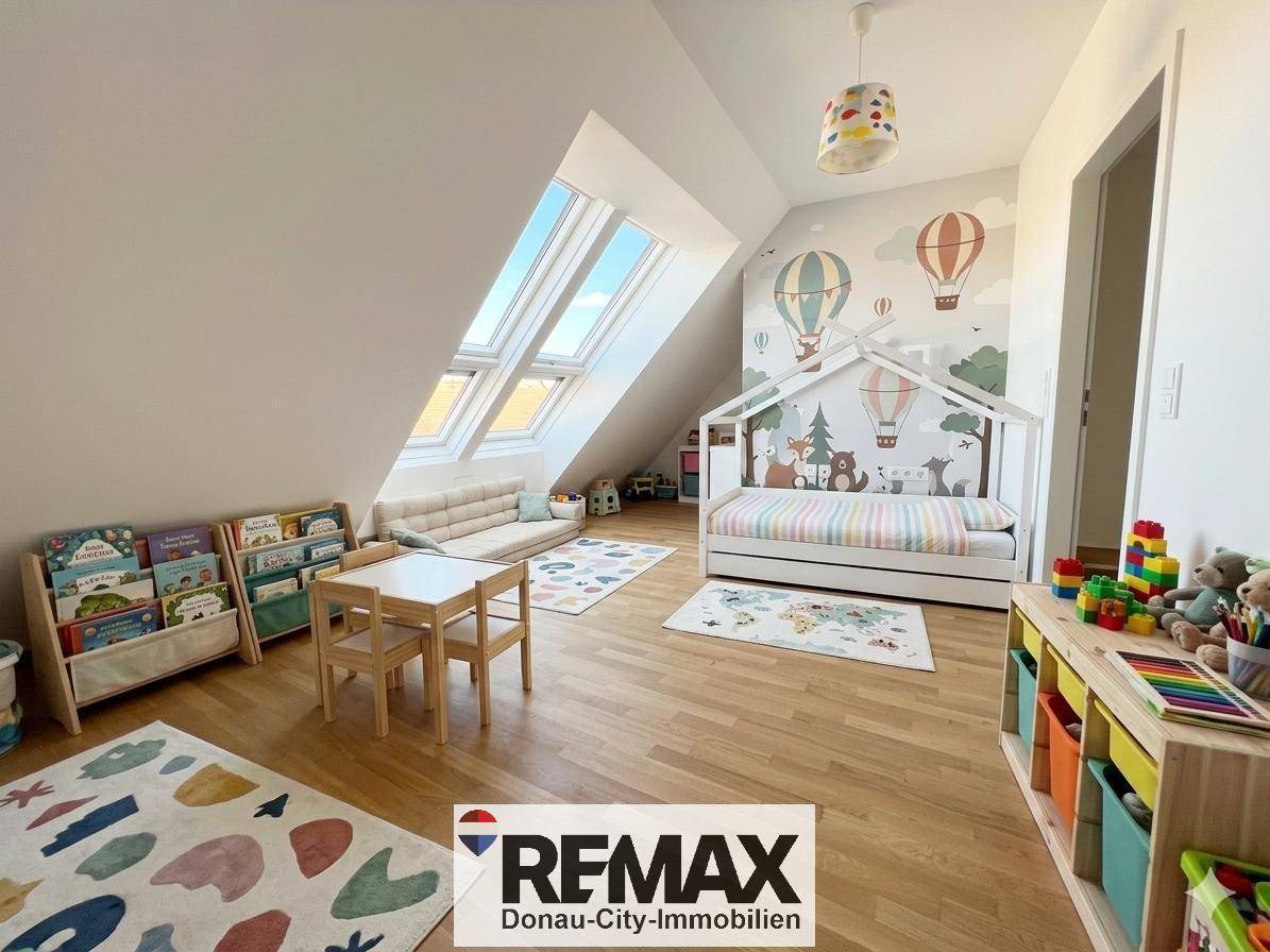 Freundliches Kinderzimmer mit Holzboden, Dachfenstern und bunter Wanddekoration.
