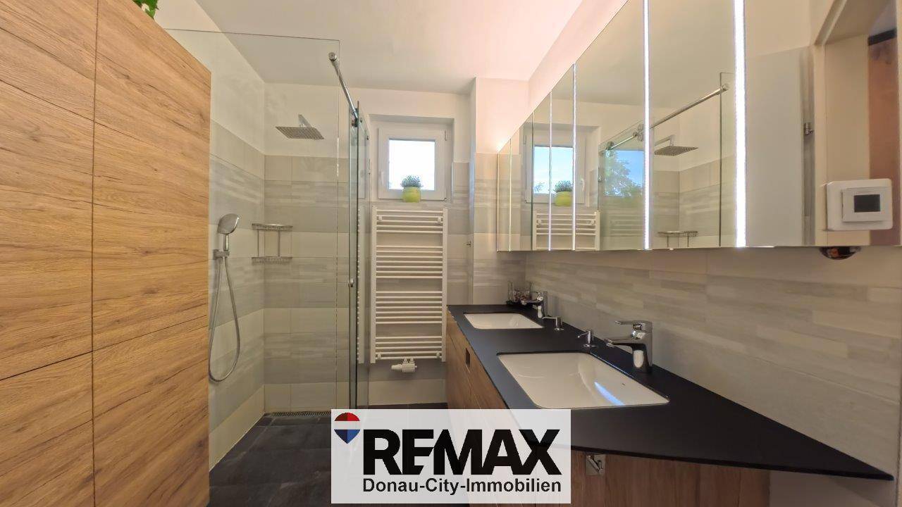 Modernes Badezimmer mit begehbarer Dusche, Doppelwaschbecken und Handtuchheizkörper.