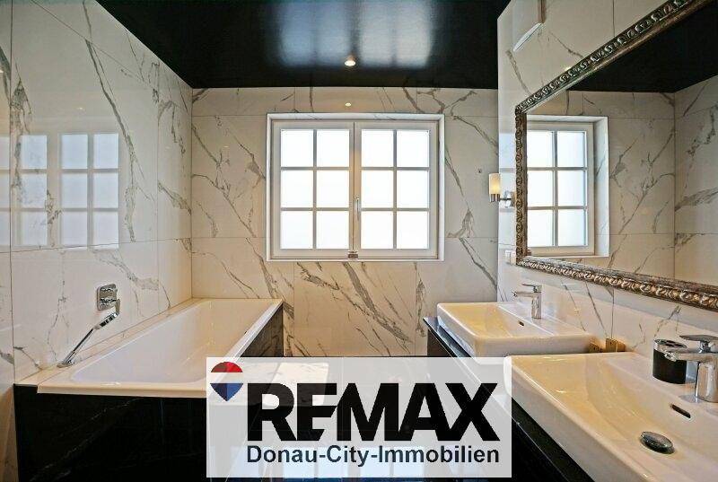 Luxuriöses Badezimmer mit Marmorfliesen, Doppelwaschbecken und integrierter Badewanne.